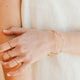 Close-up of a person's arm with gold jewelry including a bracelet and rings.
