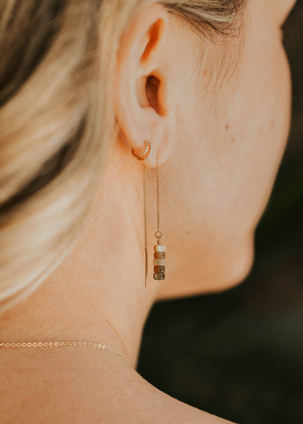 Close-up of a woman wearing a gold earring with a blurred background