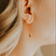 Close-up of a person wearing a gold earring with a blurred background