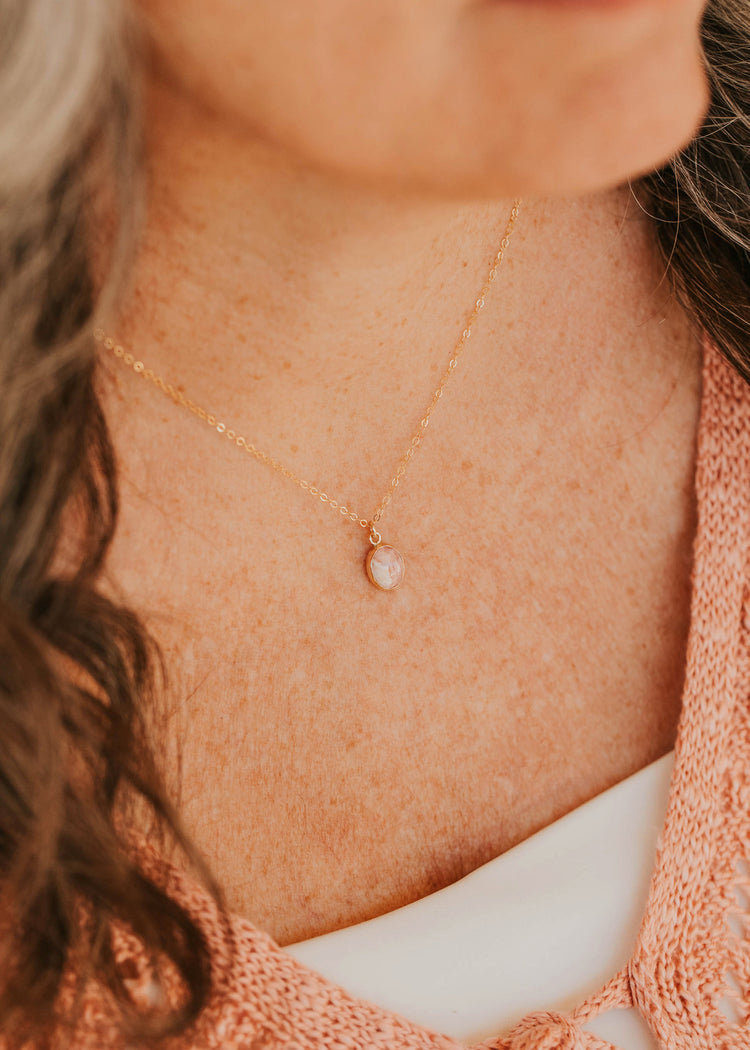 14K Gold Fill Rosalie Necklace by Hello Adorn - oval pink stone pendant worn on model's neckline with pink cardigan