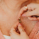 Close-up of a person adjusting a gold necklace on another person.