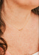Close-up of a person wearing a delicate gold necklace with small beads.