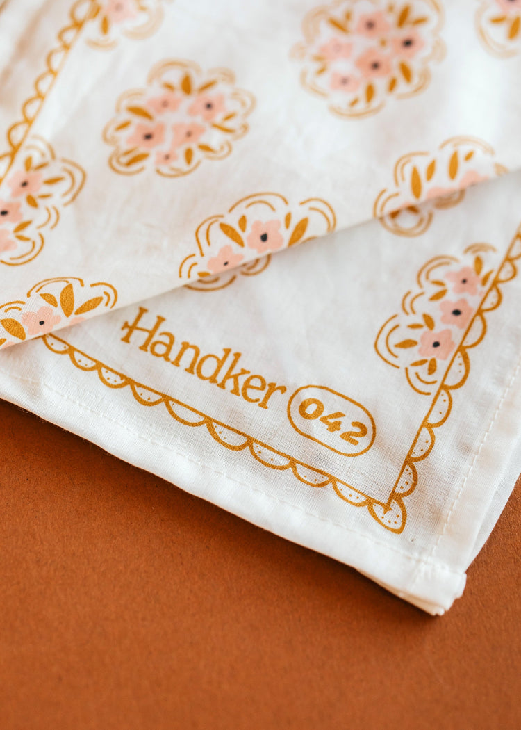 Folded handkerchief with floral pattern and 'Handker 042' text on a brown background