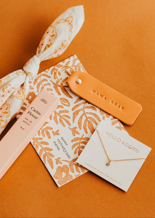 Jewelry set with floral packaging and orange tag on a brown background
