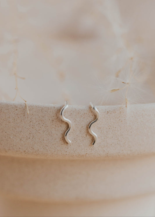 Sterling silver Tiny Wave Ear Climber earrings by Hello Adorn on a ceramic dish