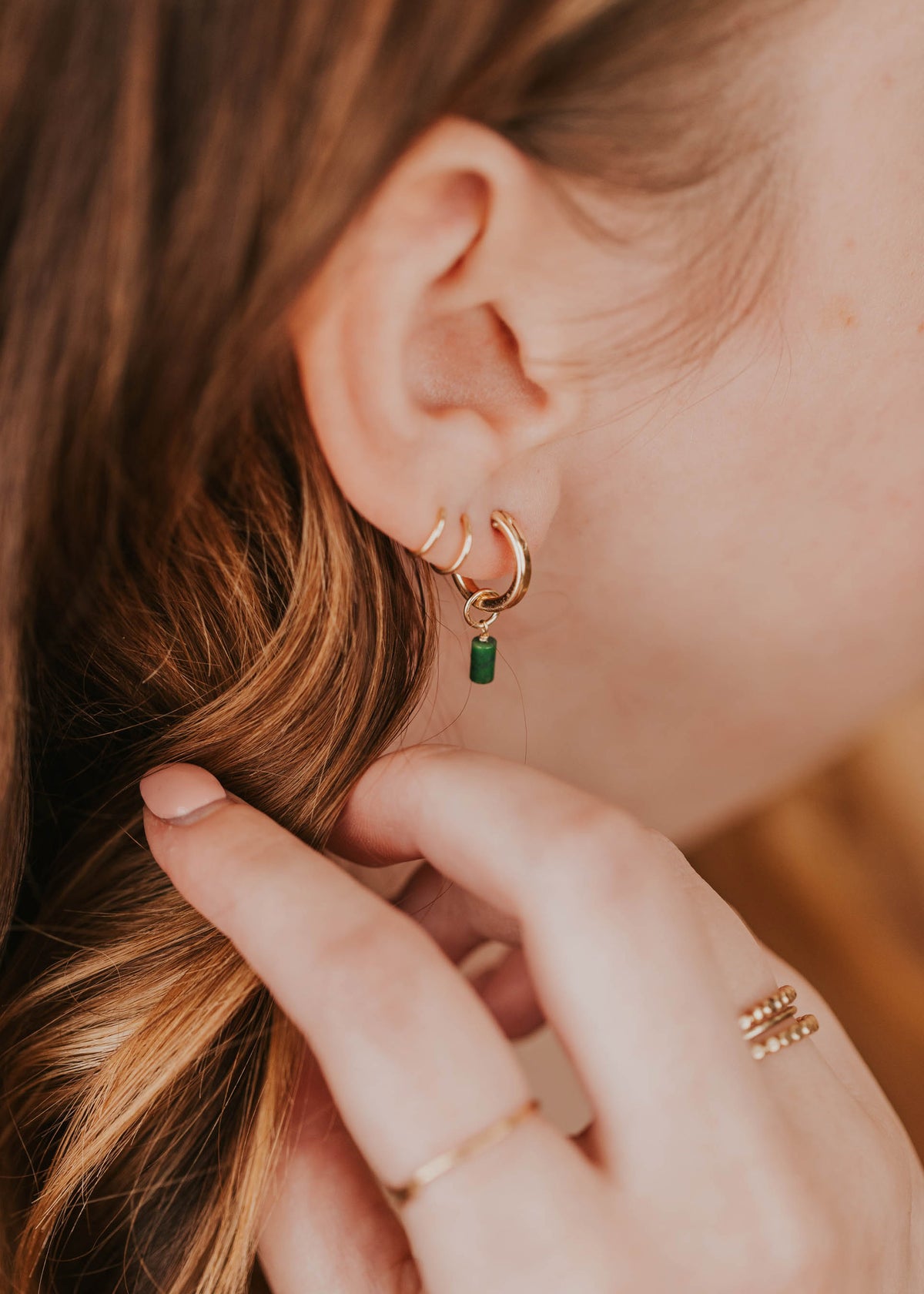 model styling tiny twist earrings with hoops and charms