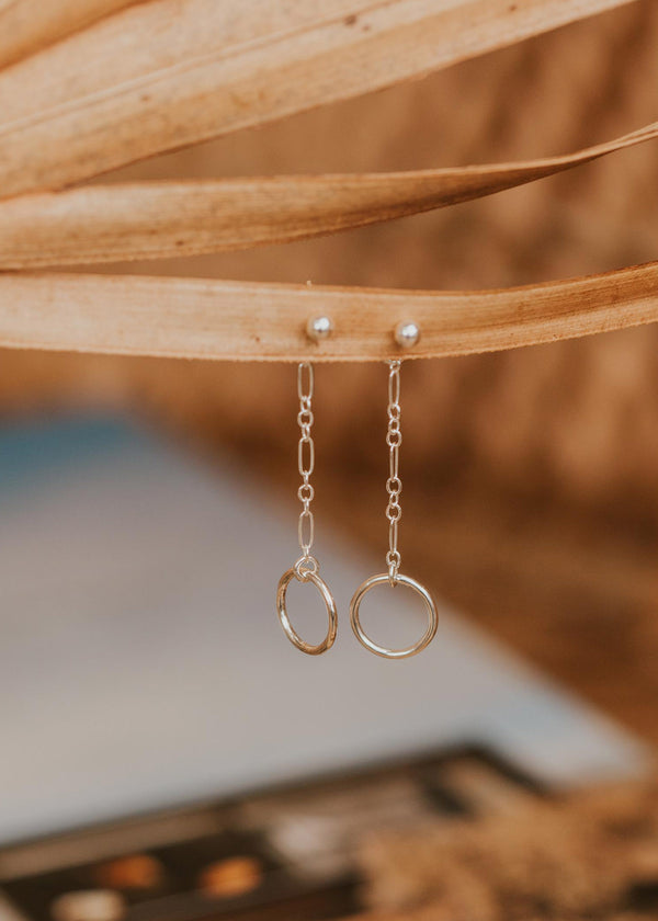 A pair of dangle earrings created by Hello Adorn in the Monday Backdrop design, a behind ear earrings pair that combines a chain drop earring with a circle drop earring.