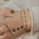 Hand with tattoos and bracelets against a light background