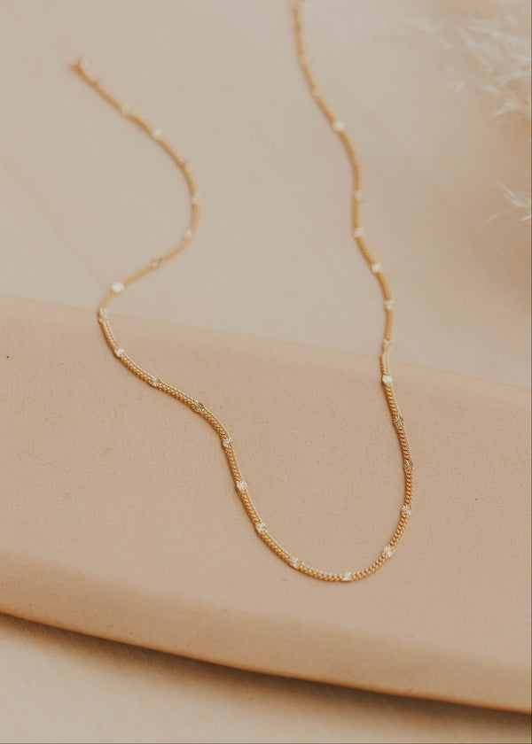 Gold necklace on a beige surface