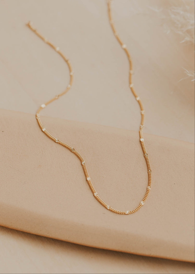 Gold necklace on a beige surface