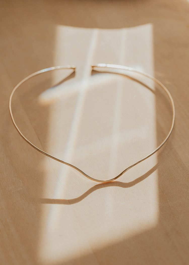 Gold necklace cuff on a beige background