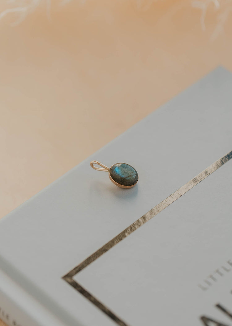 Gold pendant with a labradorite gemstone on a book