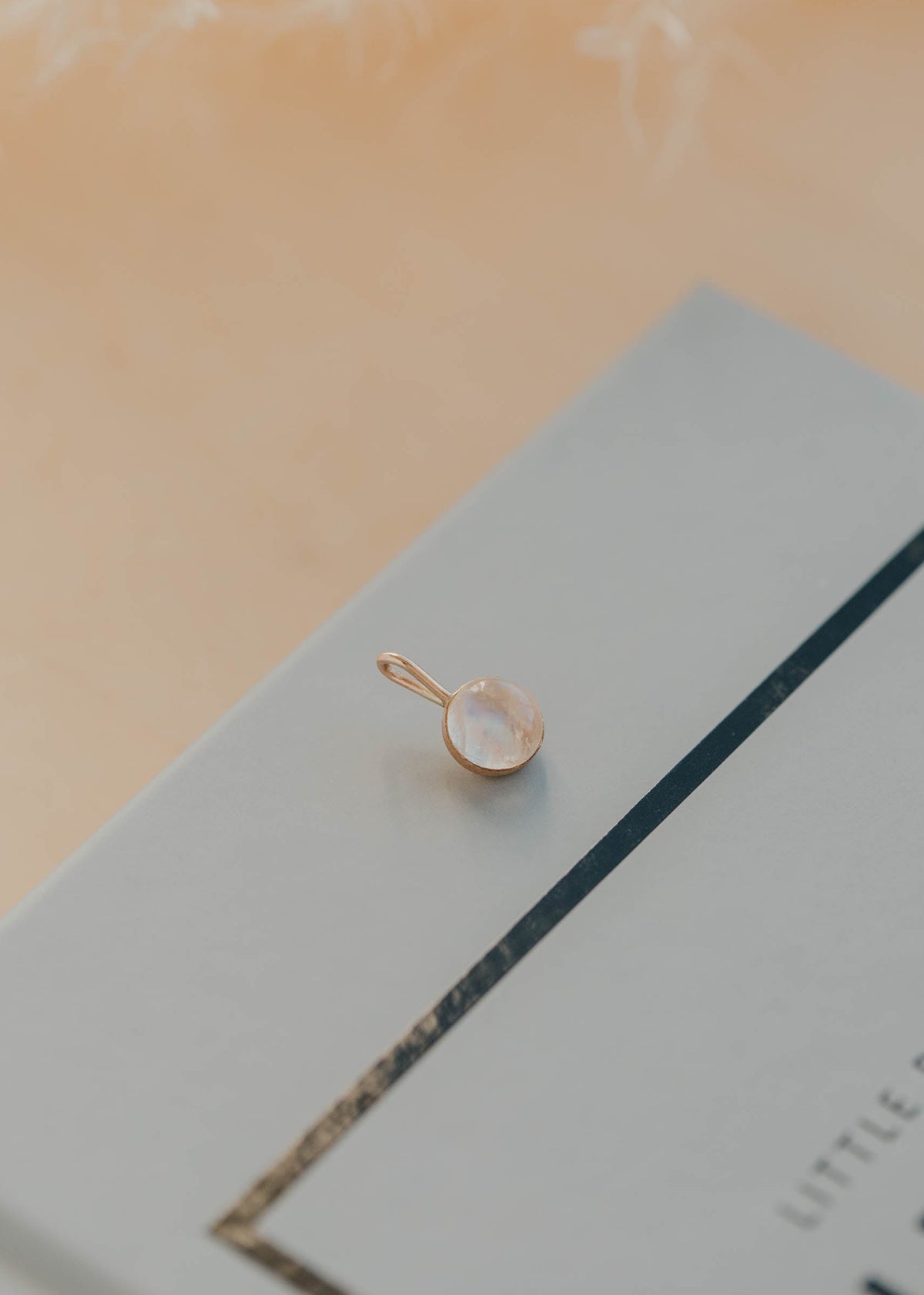 Gold pendant on a light blue card with a blurred background