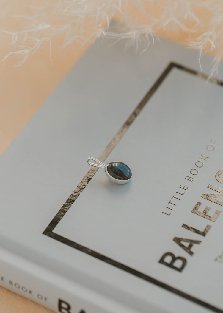 Silver pendant with a blue stone on a book