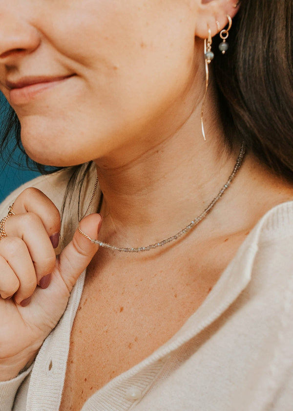 Close-up of a woman wearing a necklace with a blue background