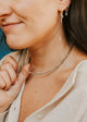 Close-up of a woman wearing a necklace with a blue background
