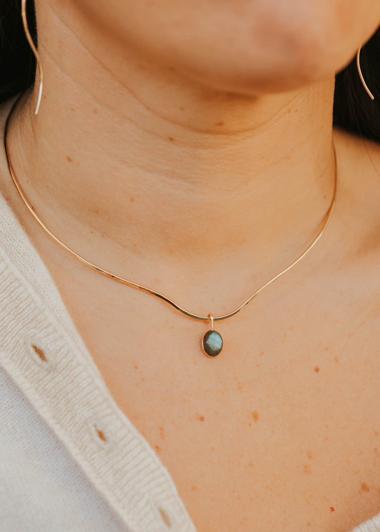 Close-up of a person wearing a gold necklace with a small pendant.