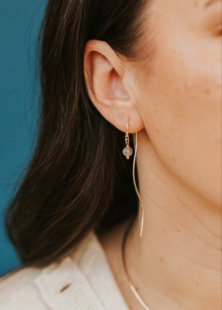 Close-up of a person wearing gold earrings against a blue background