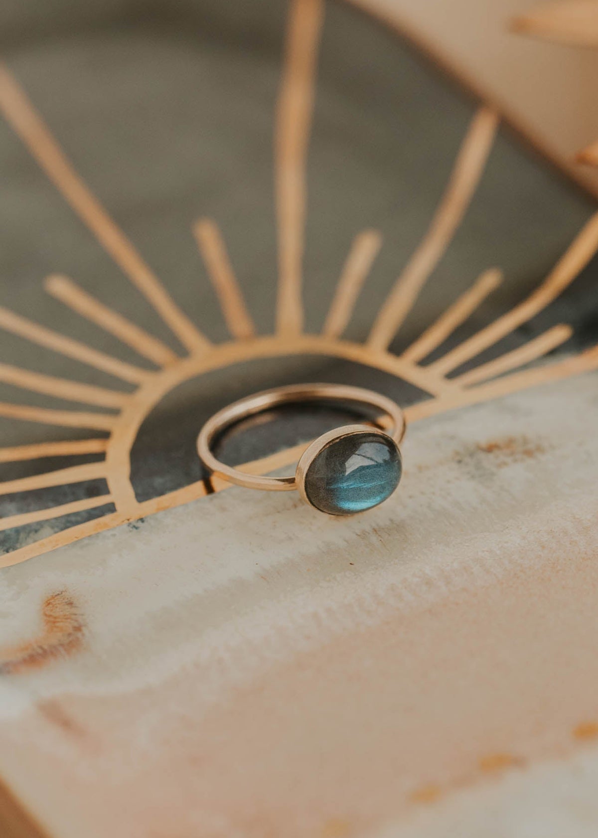 Decorative ceramic plate with sunburst design and central gemstone on a textured surface.