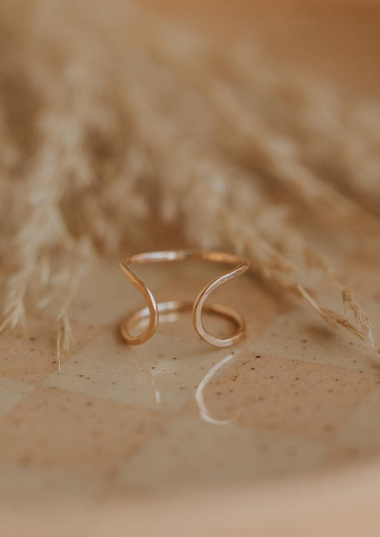 A piece of wire ring jewelry that is handmade and created into the Revolve Ring, an open ring style by Hello Adorn shown in 14k gold fill.