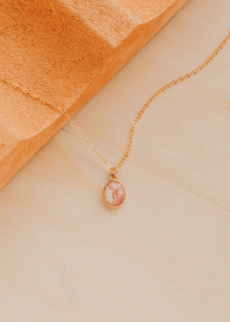 14K Gold Fill Rosalie Necklace by Hello Adorn - oval pink stone pendant on delicate chain against terracotta prop