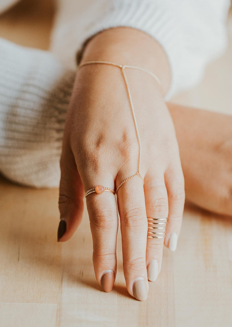 Beaded ring used to create a ring stack in 14k gold fill styled with a hand chain, above the knuckle ring, and a gemstone ring by Hello Adorn. 