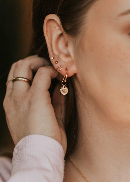 model showing hoop charms in her ear styled with tiny twist earrings