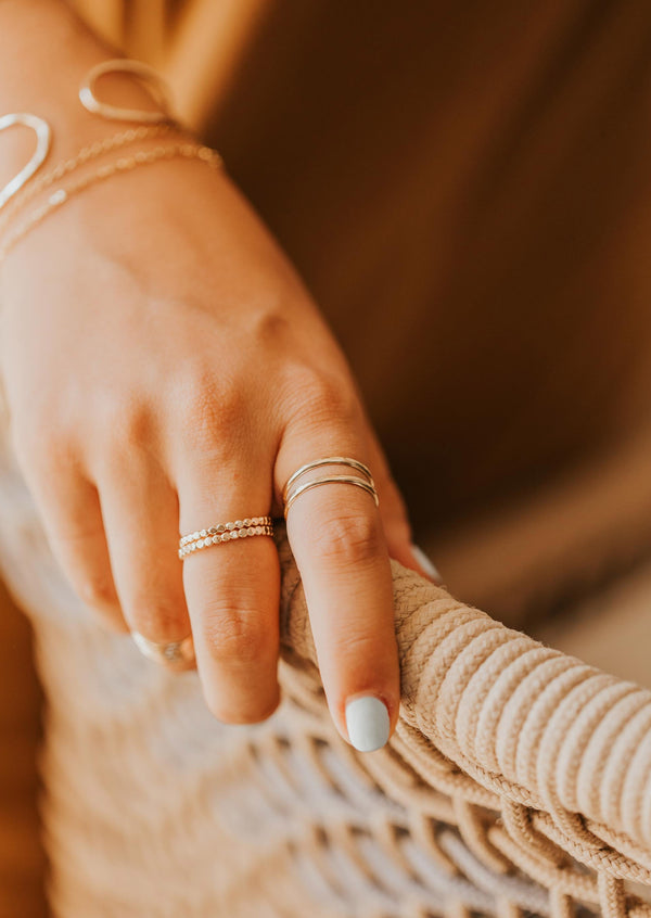 A 3 ring stack featuring two confetti bands created with a hammered ring and beaded ring styled with a thicker wire wrap ring paired with a bracelet stack by Hello Adorn.