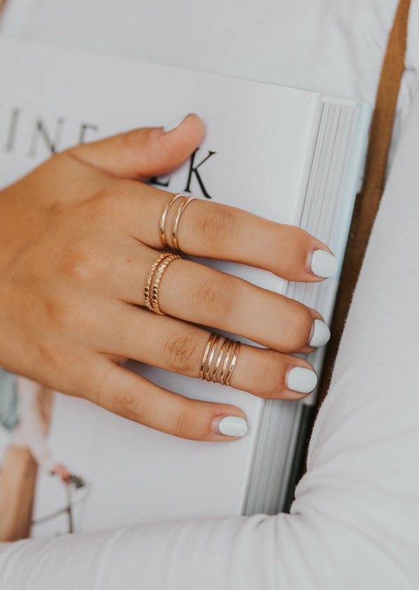 Two confetti bands styled on a models hand with midi wrap above the knuckle ring and 14k gold fill wrap ring by Hello Adorn.