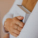 A gold ring stack using a statement ring and two stacking rings with styles of confetti rings which is a hammered ring and a wrap ring using thicker wire styled by Hello Adorn.