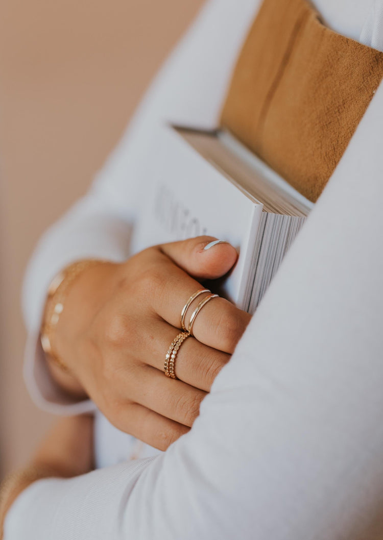 A gold ring stack using a statement ring and two stacking rings with styles of confetti rings which is a hammered ring and a wrap ring using thicker wire styled by Hello Adorn.