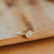 Gold ring with a round stone on a beige surface