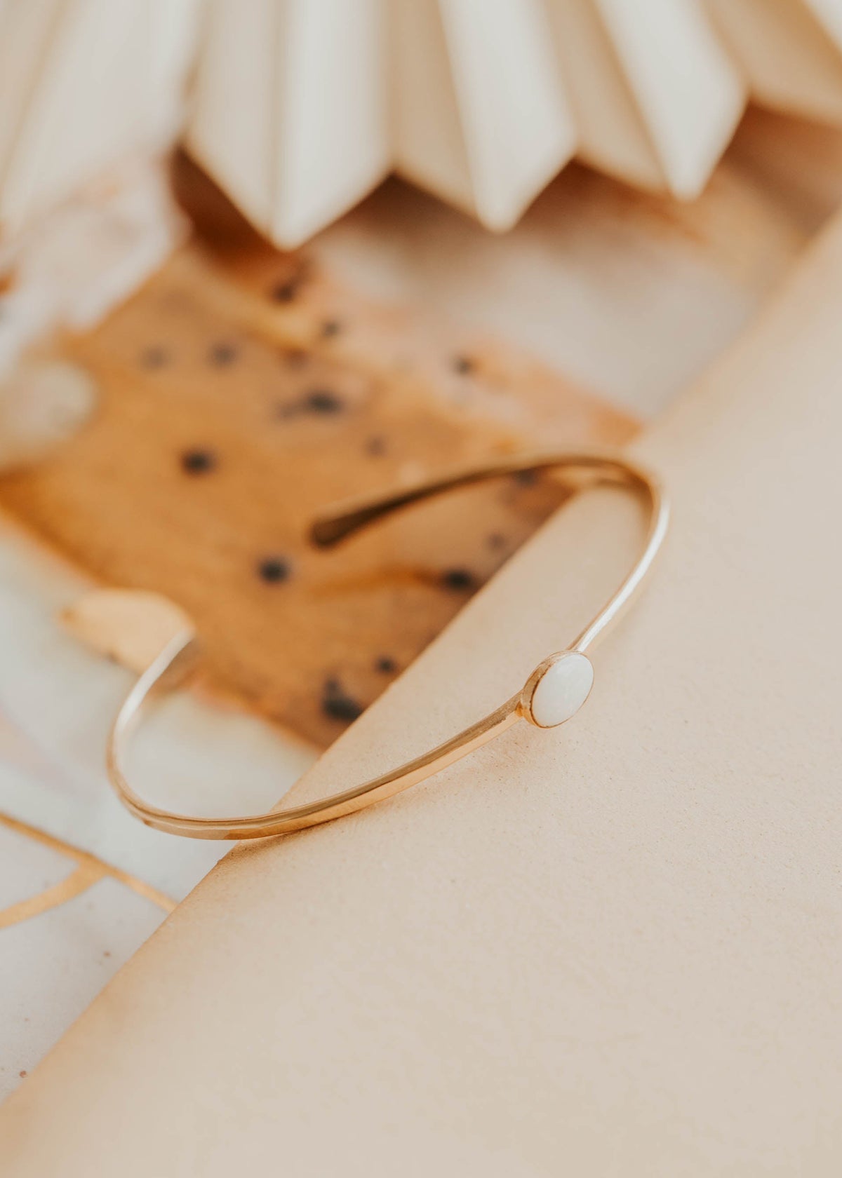 Gold bracelet on a textured beige surface with a blurred background