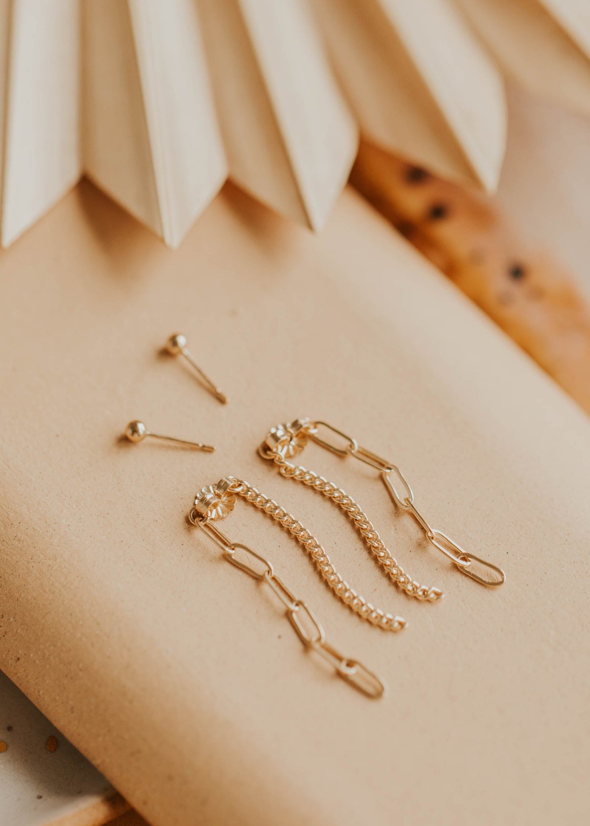 Gold jewelry pieces on a beige surface with a textured background