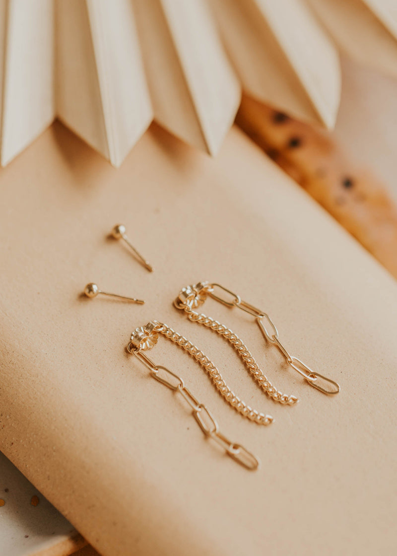 Gold jewelry pieces on a beige surface with a textured background