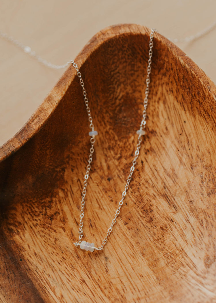 Delicate gold necklace with small gemstones on a wooden surface