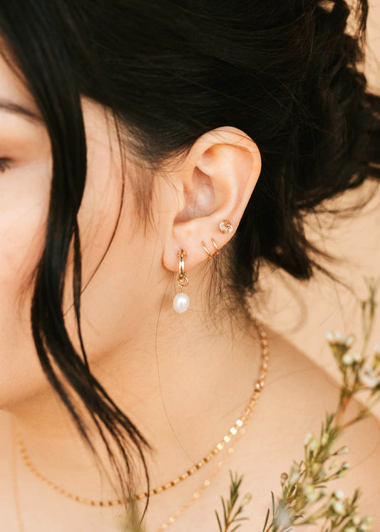 Close-up of a person wearing pearl earrings with a blurred background