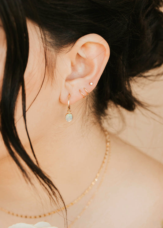 Close-up of a person wearing gold earrings with a soft background