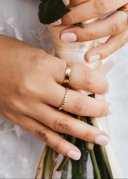Close-up of hands holding a bouquet with gold rings on fingers