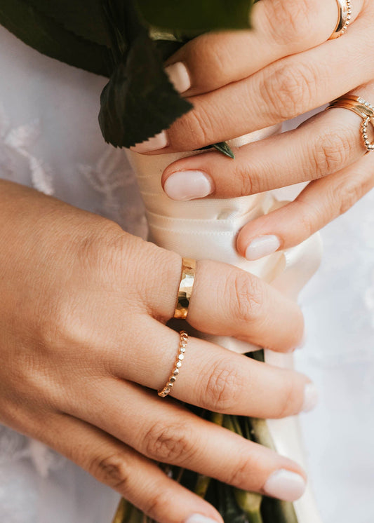 Close-up of hands holding a bouquet with gold rings on fingers