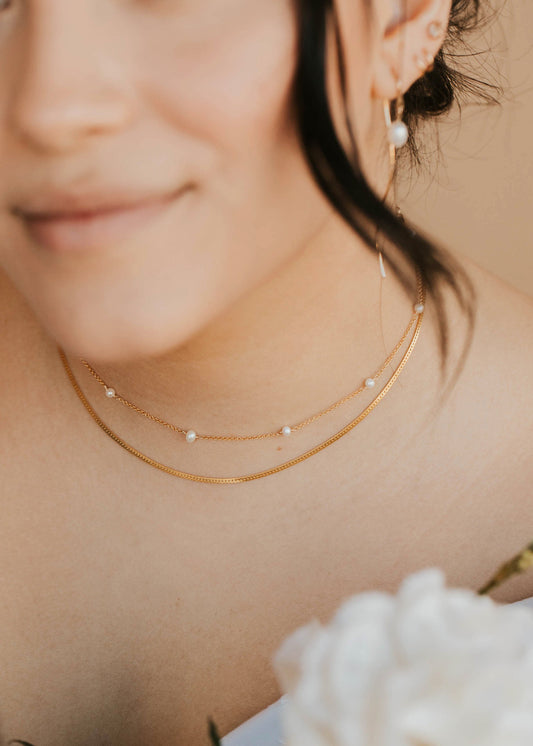 Close-up of a woman wearing gold necklaces and earrings with a blurred background