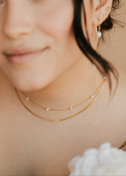 Close-up of a woman wearing gold necklaces and earrings with a blurred background