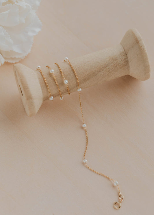Gold necklace with pearls on a beige surface