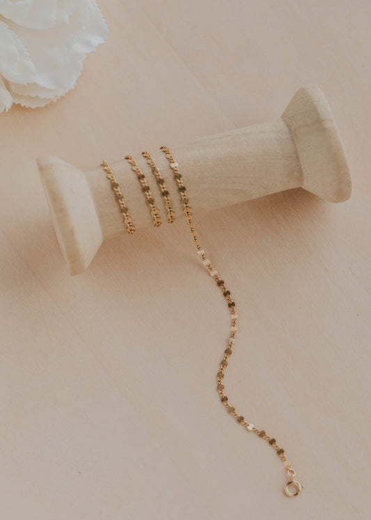Gold necklace on a beige spool with a soft focus background
