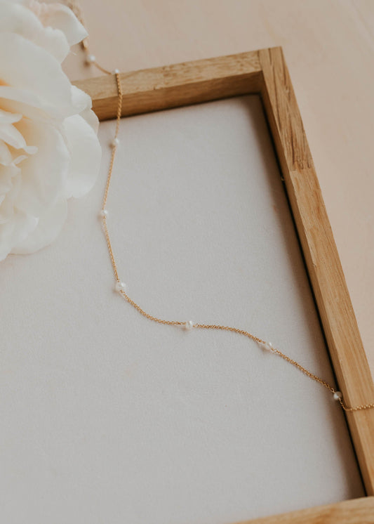 Necklace with pearls displayed in a wooden frame against a light background