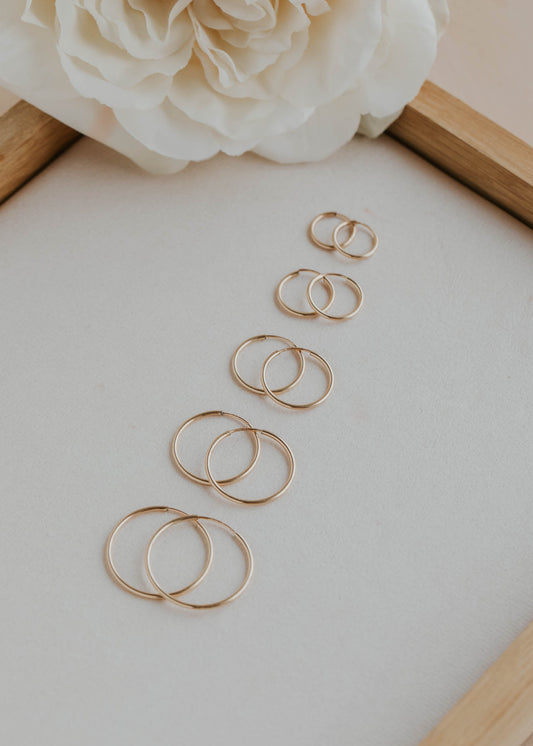 Gold rings arranged on a light surface with a white flower in the corner.
