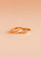 Two gold rings on a beige background