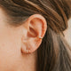 Close-up of an ear with gold earrings and hair.
