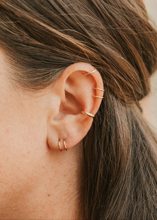 Close-up of an ear with gold earrings and hair.