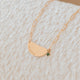 Gold necklace with a green gemstone on a textured beige surface